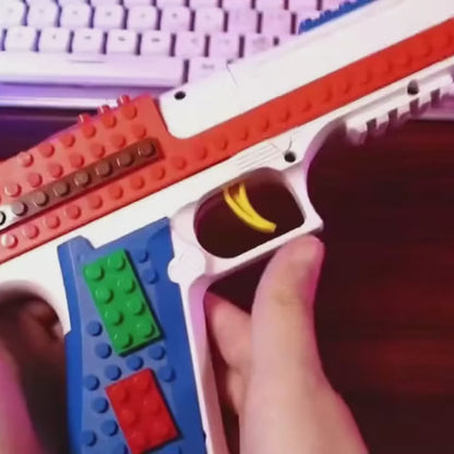 Desert ShellBlaster Brick in hand: building bricks clipped on, casing loaded, toy darts fired with casing ejection